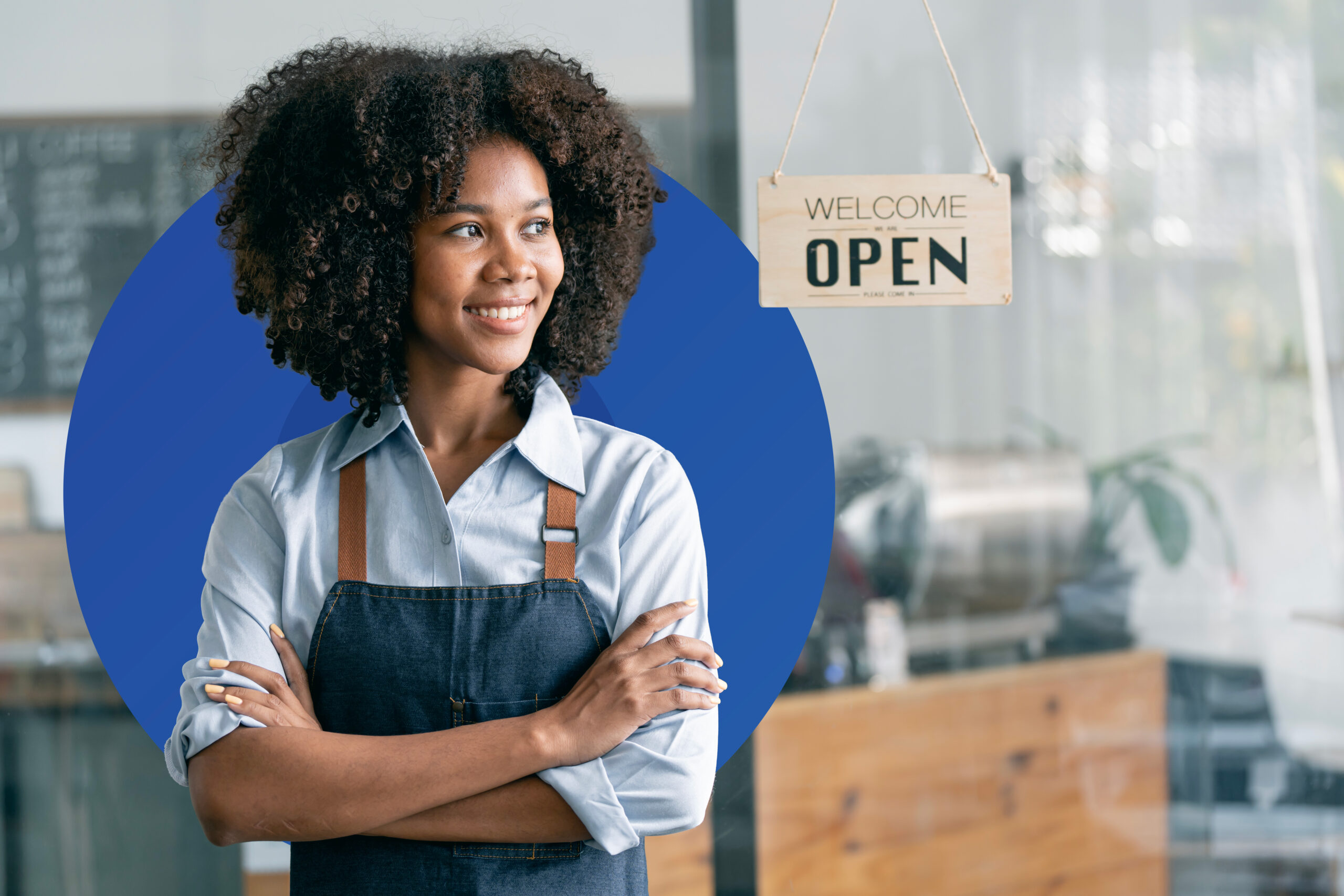Smiling self-employed business owner standing in front of her store with an open sign